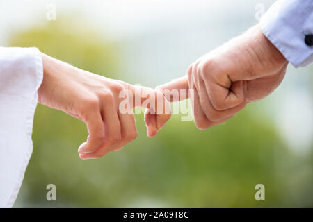 Close-up di amare giovane azienda ogni altro il dito contro sfondo sfocato Foto Stock