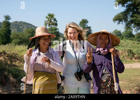 Una femmina caucasica (modello rilasciato) Tourist in posa con due tradizionale fattoria birmano le donne sulla strada vicino a Bagan Myanmar indossando Thanaka trucco per Sun P Foto Stock