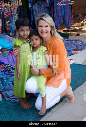 Un Caucasian turista femminile (rilasciato) con due bambini birmani indossando Thanaka trucco nel mercato all'aperto in Bagan Myanmar guardando la telecamera. Foto Stock