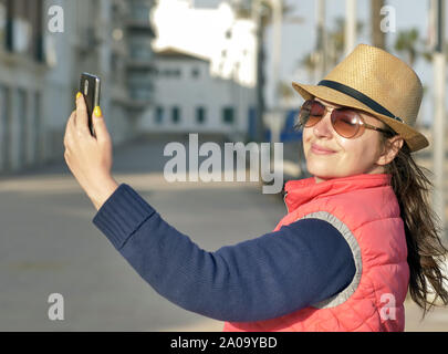 Ragazza attraente turistico a cappello e occhiali selfie rende su una soleggiata giornata autunnale Foto Stock