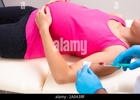 Close-up del medico la vaccinazione di giovane donna incinta sdraiato sul letto in clinica Foto Stock
