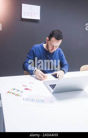 Uomo Barbuto lavorando sul computer portatile in ufficio Foto Stock
