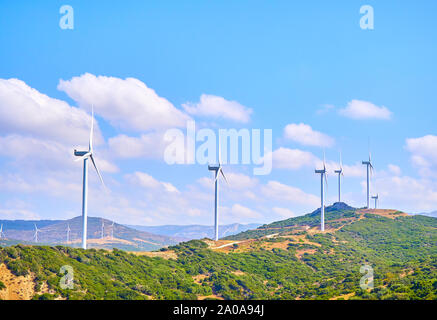 Turbine eoliche che generano elettricità tra un campo arido e un cielo azzurro sfondo per copiare lo spazio. Foto Stock