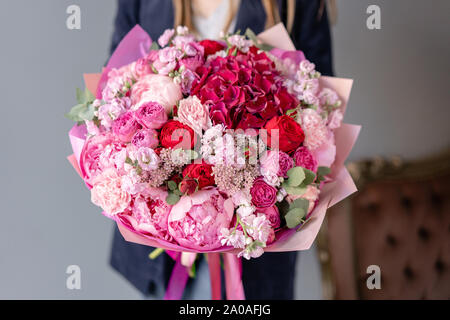 Peonie rosa e rosso hydrangea. Bouquet di fiori misti nella donna la mano. Floral concetto di shop . Bel bouquet fresco. Consegna di fiori a domicilio. Rosso Foto Stock