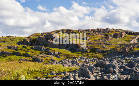 Una collina rocciosa con erba e muschio. Oltre la collina, il bianco delle nuvole play catch-up, la creazione di figure inimmaginabili. Primordiale potenza naturale si trova nel nord Foto Stock