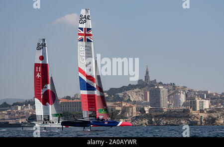 Vicino a vela tra Giappone Team SailGP skipper da Nathan Outteridge e Gran Bretagna Team SailGP helmed da Dylan Fletcher come essi navigano verso la cattedrale di Notre Dame de la Garde durante una pratica gara precedendo la finale SailGP evento della stagione 1 a Marsiglia, Francia. Foto Stock