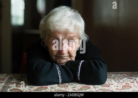 Ritratto di un solitario grey-haired vecchia donna nella sua casa. Foto Stock