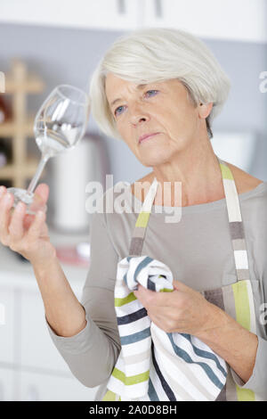 Donna matura per la pulizia del vetro del vino Foto Stock