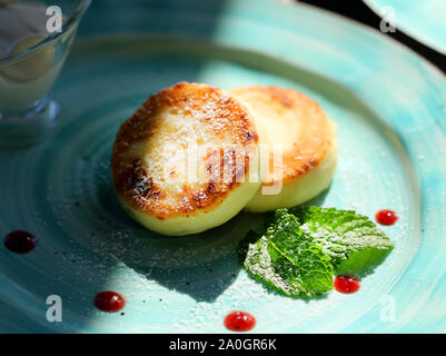 Foto macro di deliziosi big cheesecake con menta su una piastra illuminata dal sole Foto Stock