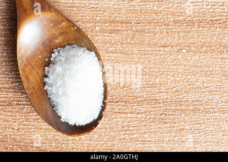 Lo zucchero in un cucchiaio di legno su un tavolo di legno. Messa a fuoco selettiva Foto Stock