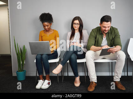 Multietnica richiedenti lavoro occupato con computer portatili e smartphone la preparazione per il reclutamento di parlare in ufficio Foto Stock