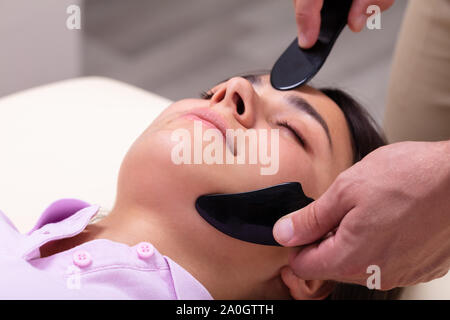 Bella giovane donna faccia Gua Sha Massaggio a Asian Clinica di Bellezza Foto Stock