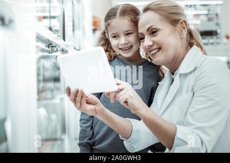 Farmacia lavoratore considerando le vitamine assortimento via tablet con una ragazza Foto Stock