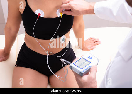 Medico applicazione monitor Holter dispositivo sul corpo della donna per il monitoraggio quotidiano di un elettrocardiogramma Foto Stock