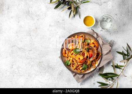 Spaghetti di mare con conchiglie, gamberi, calamari su sfondo grigio. Mediterranea italiana il concetto di cibo Foto Stock