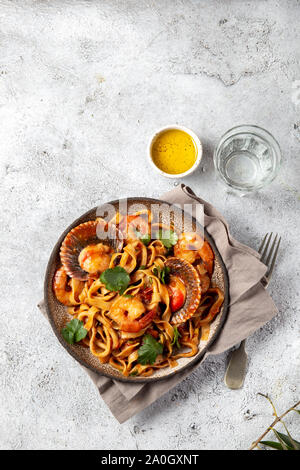 Spaghetti di mare con conchiglie, gamberi, calamari su sfondo grigio. Mediterranea italiana il concetto di cibo Foto Stock