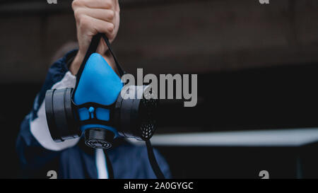 Respiratore di protezione semi maschera per gas tossici.L'uomo preparare alla protezione da usura dell'inquinamento atmosferico. Chi detiene un respiratore, il braccio esteso in avanti Foto Stock