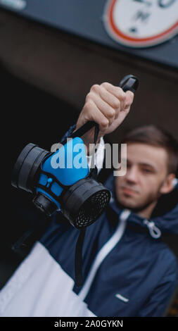 Respiratore di protezione semi maschera per gas tossici.L'uomo preparare alla protezione da usura dell'inquinamento atmosferico. Chi detiene un respiratore, il braccio esteso in avanti Foto Stock