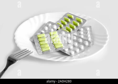 Pillole diverse su una piastra con posate. Il concetto di prescrizione di farmaci per la perdita di peso. Mezzi per la soppressione di appetito. Foto Stock
