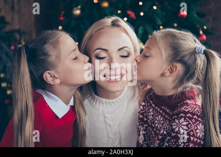 La tenerezza di gara momenti di svago. Incurante mamma chiudere occhi fanno sorriso toothy face tipo affascinante ed elegante preteen bionda in morbido maglione pouted labbra kis Foto Stock