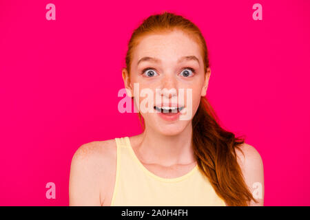 Close-up ritratto della bella carino incantevole adorabili attraente sognanti positivo i Capelli rossi ragazza in tanktop, omg, aperto bocca, isolate su bright vivid fu Foto Stock