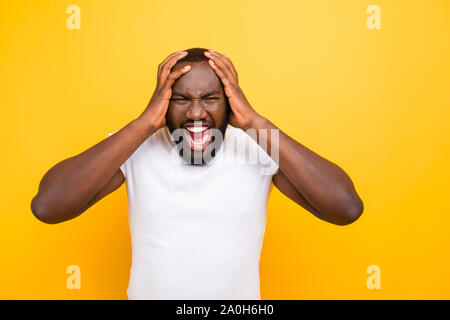 Bello attraente manly sportive wild crazy mulatto uomo in bianco t-shirt con denti di lucido, gridando, toccando la testa, isolate su bright vivid yello Foto Stock