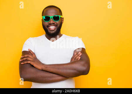 Ritratto di Allegro bel lieto mulatto uomo in bicchieri di colore, bracci ripiegati, isolate su bright vivid sfondo giallo Foto Stock