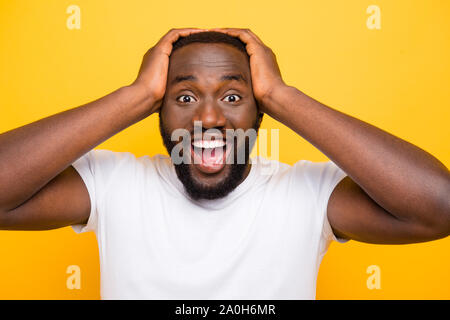 Ritratto di bello scioccato mulatto uomo con setole, tenendo la testa con le palme, aperto bocca, isolate su bright vivid sfondo giallo Foto Stock