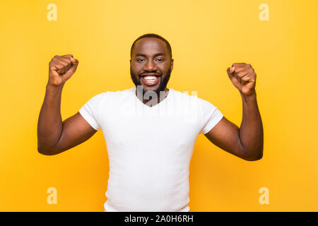 Ritratto di Allegro eccitato lieti mulato uomo, mostrando il gesto vincente, celebrando e isolate su bright vivid sfondo giallo Foto Stock
