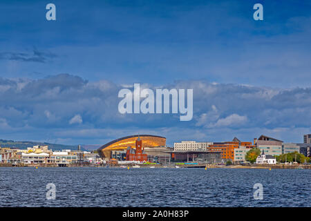 Un albero di sole illumina il Millennium Centre e il Rosso Mattone di Edificio Pierhead sulla Baia di Cardiff iconici waterfront, Glamorgan, Wales, Regno Unito Foto Stock