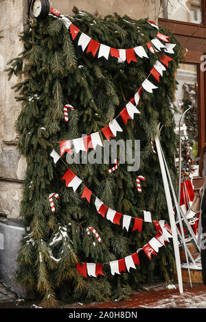 Natale decorazioni di strada. Elegante natale rami di abete con bandiere di carta garland e candy cane in corrispondenza della parte anteriore del negozio al mercato di vacanza nella strada della citta'. Spa Foto Stock