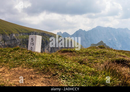 Pietra di confine tra Slovenia e Italia sulla cima del Mangart sella, Mangartsko sedlo. nei pressi del Mangart Road. Alpi Giulie in background. Foto Stock