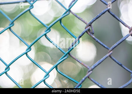 Nuovo collegamento a catena accanto a una vecchia catena collegamento recinto con un sfondo bokeh di fondo Foto Stock