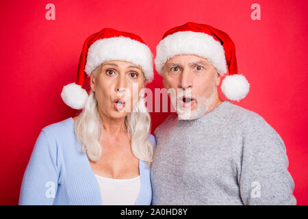 Closeup ritratto di due stupiti confuso perplesso gente affascinante bellissima grey-haired marito e moglie granny nonno aperto bocca isolato sulla parte posteriore di colore rosso Foto Stock