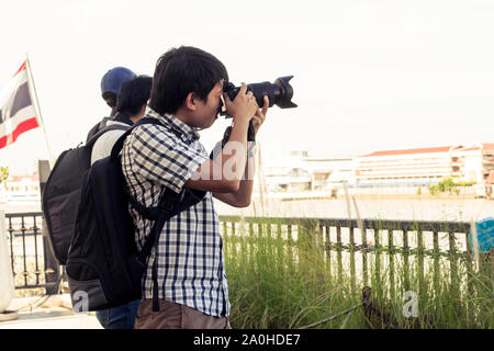 I turisti maschi di scattare foto con una fotocamera mentre si è in viaggio. Le gite sono paesaggi fotografati in Thailandia. Un gruppo di uomini sono in piedi la fotografia sul th Foto Stock