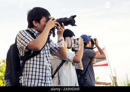 I turisti maschi di scattare foto con una fotocamera mentre si è in viaggio. Le gite sono paesaggi fotografati in Thailandia. Un gruppo di uomini sono in piedi la fotografia sul th Foto Stock