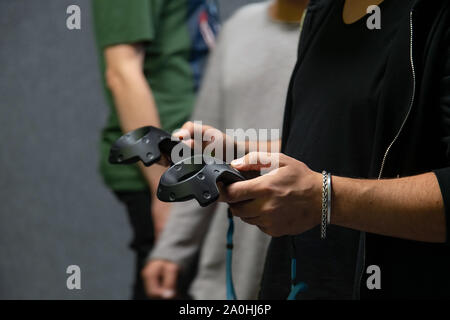 Giovane uomo la riproduzione di gioco di realtà virtuale mentre indossa la cuffia e il controller holding game pad in mani Foto Stock