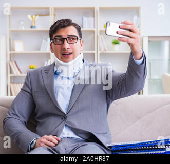 L'uomo nel rinforzo del collo collare cervicale lavorando da casa il telelavoro Foto Stock