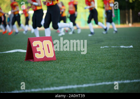 Foto del campo di calcio con il numero trenta in esecuzione i giocatori di calcio su sfondo sfocato sul giorno di estate Foto Stock