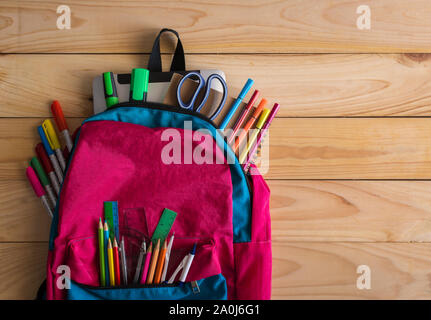 Scuola zaino e forniture scolastiche sul tavolo di legno dello sfondo. Si torna a scuola concetto. Foto Stock