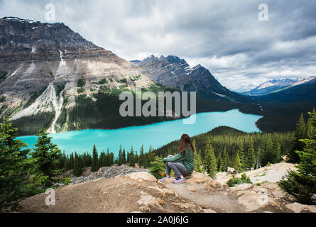 Donna seduta su roccia affacciato sul Lago Peyto nelle Montagne Rocciose. Foto Stock