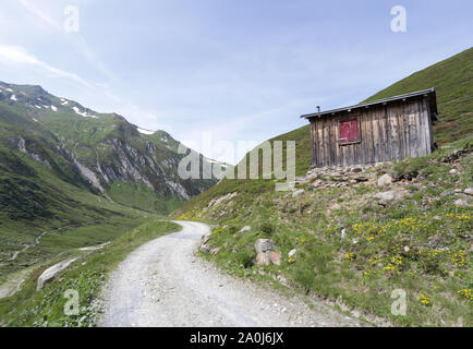 Una capanna alpina accanto a una strada di ghiaia alta in Swiss Alp montagne Foto Stock