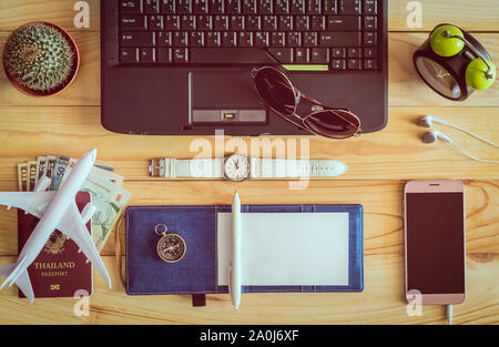 Vista superiore del notebook, penna, occhiali da sole, tazza di caffè, passaporto, denaro, telefono cellulare, auricolari, orologio da polso, cactus, orologio, il mouse del computer e sulla bussola Foto Stock