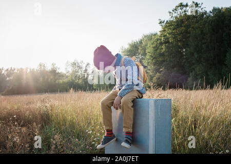 I giovani della scuola ragazzo seduto su un post a casa a piedi al tramonto Foto Stock