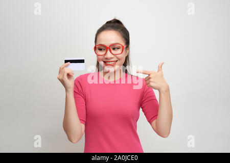 Foto di bella giovane donna isolato su sfondo bianco. Guardando la telecamera winking tenendo la carta di credito. Foto Stock