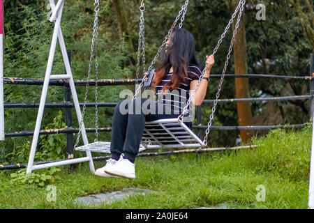 Una donna su un altalena in un parco Foto Stock