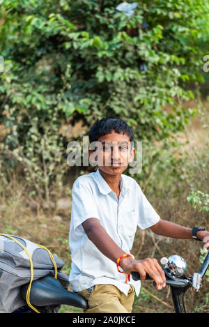 PUTTAPARTHI, India - 29 novembre 2018: Indiano ragazzo su una bicicletta. Verticale. Con il fuoco selettivo Foto Stock