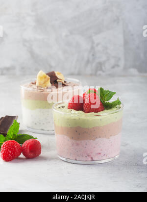 Chia budino di sementi con tre sapori, cacao, matcha e fragola con yogurt, cioccolato e foglie di menta, orientamento verticale Foto Stock