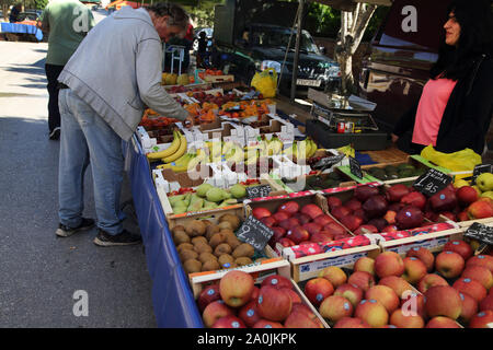 Vouliagmeni Grecia frutta uomo stallo guardando le ciliegie Foto Stock