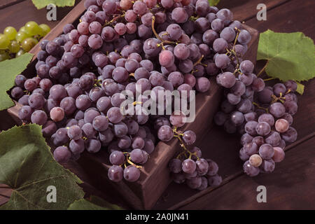 Fresche uve rosse in cassa in un tavolo di legno. Vitigno rosso Foto Stock